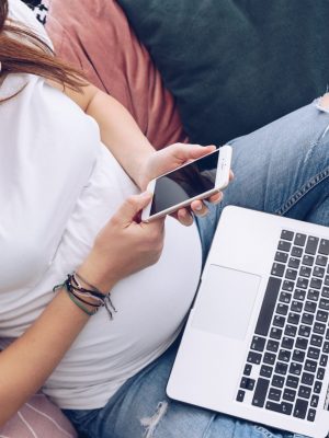 Young pregnant woman is working on laptop at her home, makes a call